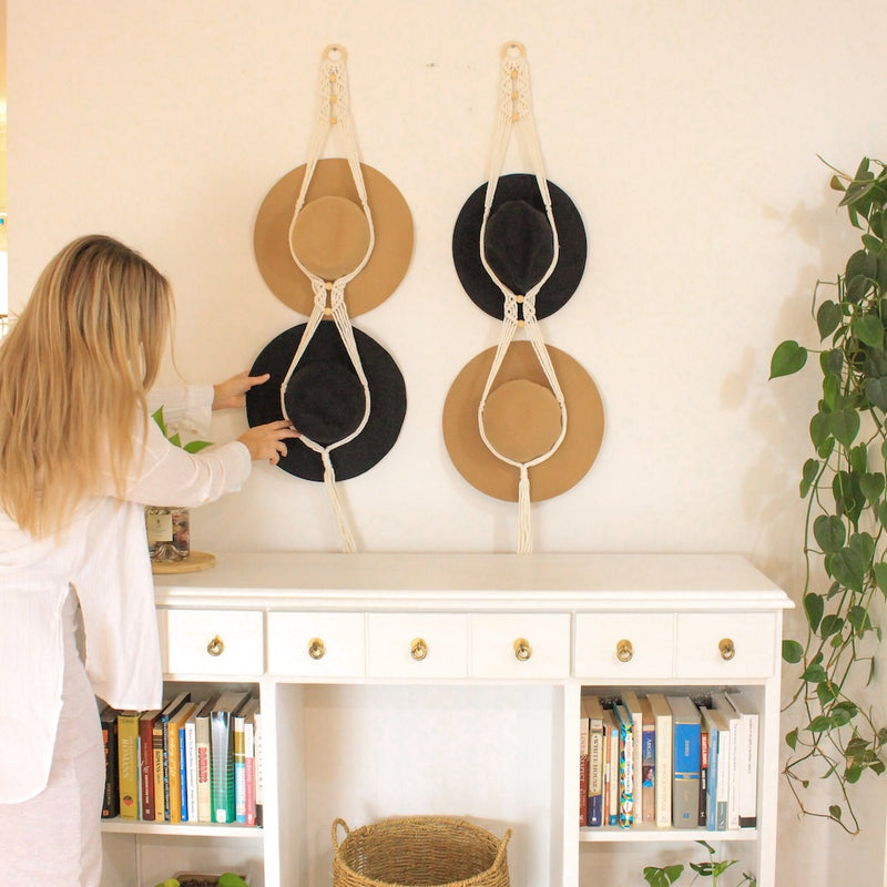 Macrame Hat Hangers are hung on a wall holding 4 black and tan akubra style wide brim hats