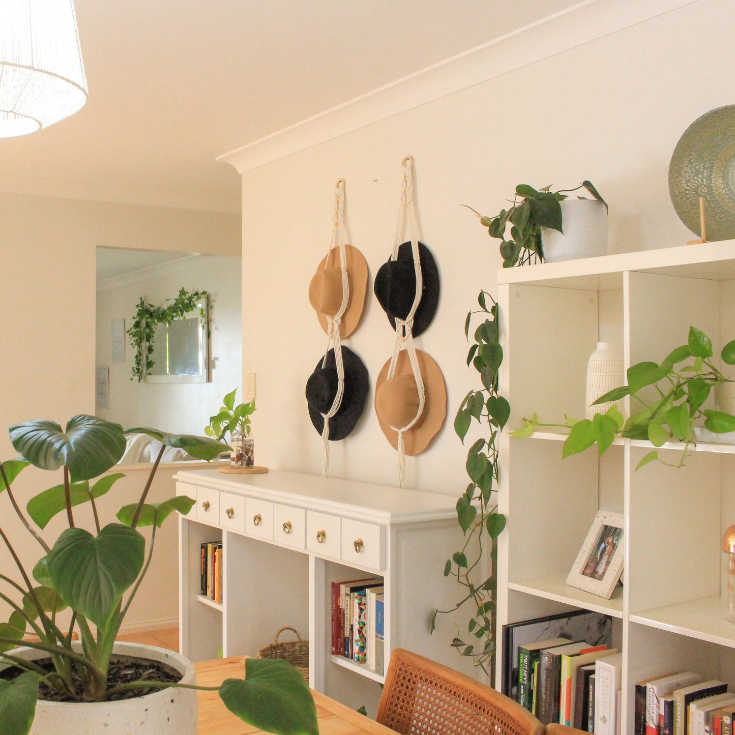 Macrame Hat Hangers in a living dining room with green plants wooden and white furnishings and books
