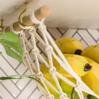 a close up of the gold hooks that are included for free with every purchase of a macrame fruit hammock. the cotton is woven to support the fruit. below the kitchen cabinet but this item can also be used in a rv, van or caravan.