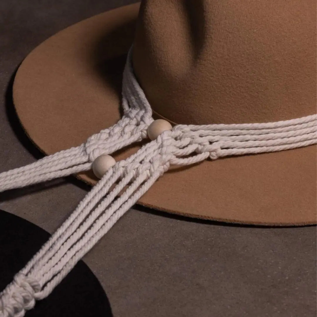 Close up macrame hat hanger with a brown and black akubra hat.